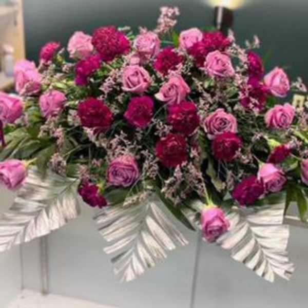 Pink and magenta rose arrangement on a white casket