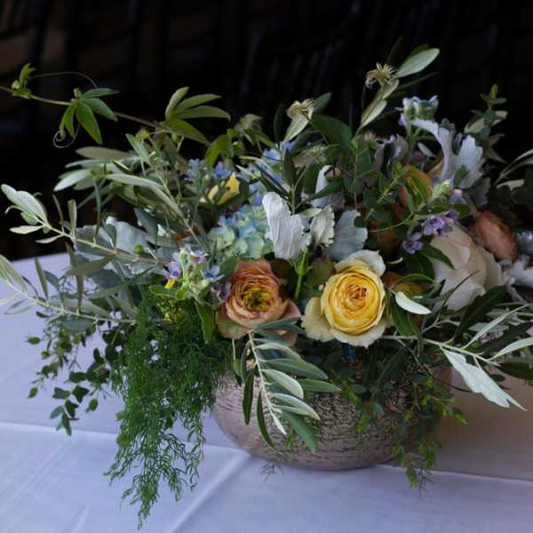 Low floral centerpiece with yellow and peach roses in a shallow bowl