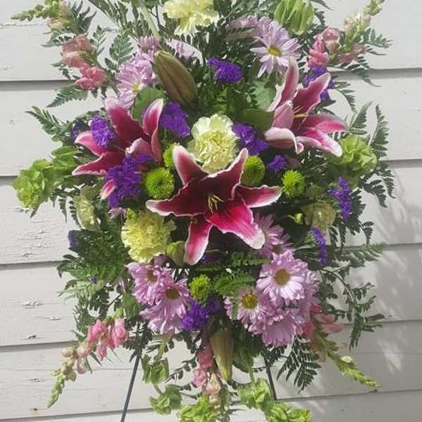 Standing floral spray with pink lilies and purple daisies on an easel