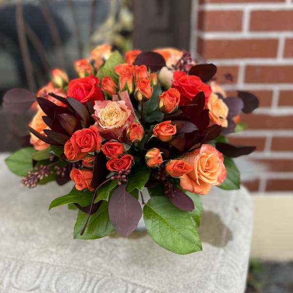 Bouquet of orange and red roses with dark foliage