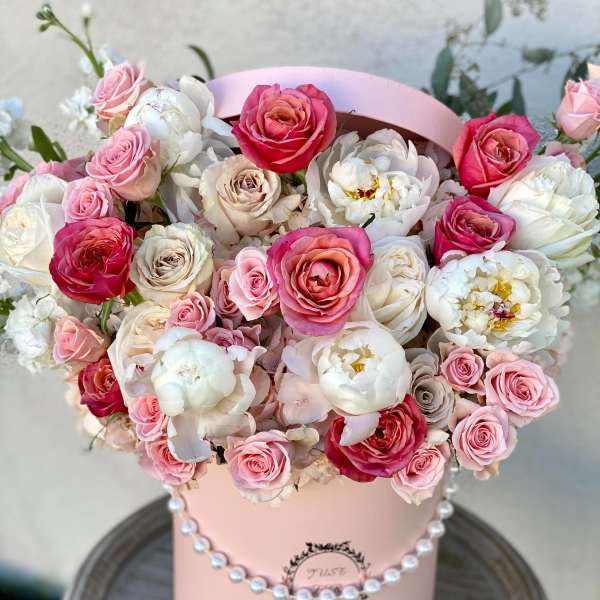 Pink and white roses arranged in a pastel pink hat box