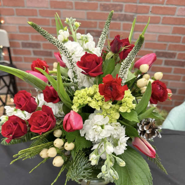 Red roses and white flowers arranged in a low vase with pink tulips