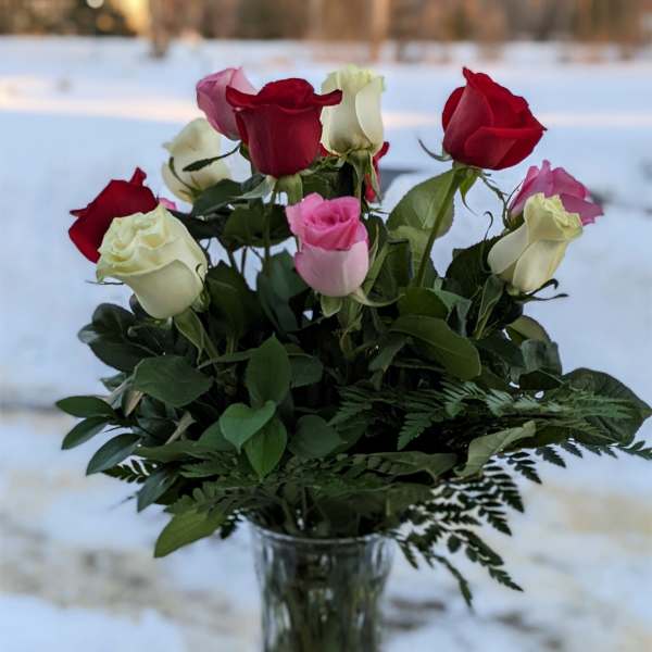 Bouquet of red, pink, and white roses in a clear glass vase