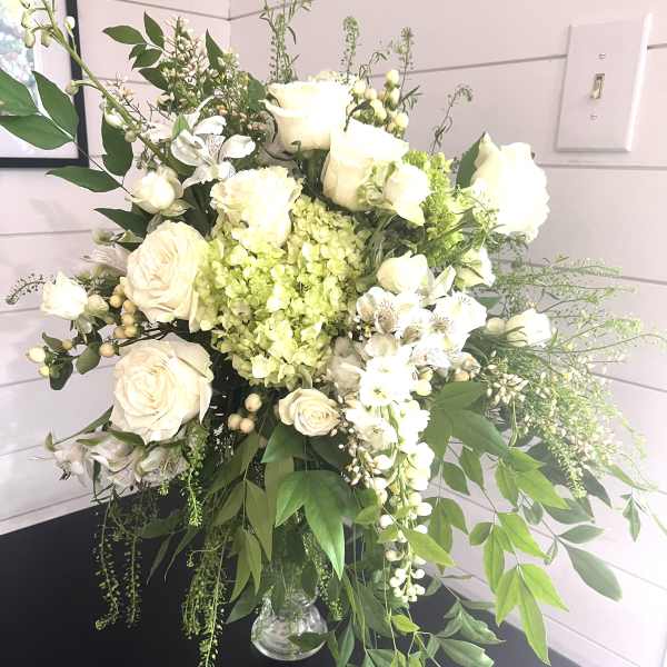 White roses and mixed white flowers in a glass vase