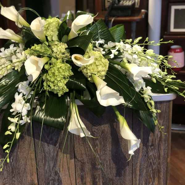 White calla lilies and orchids arranged with green hydrangeas