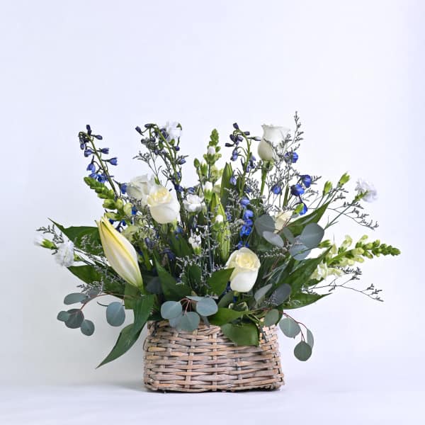 White and blue floral arrangement in a woven basket