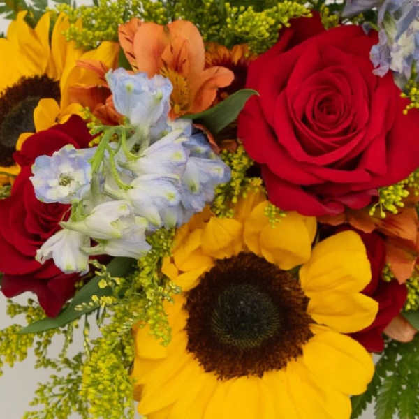 Bouquet of red roses and yellow sunflowers with blue flowers