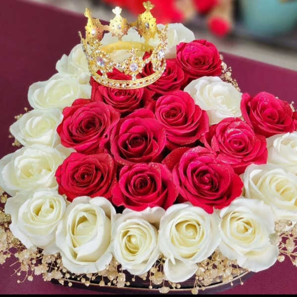 Red and white rose arrangement topped with a gold crown