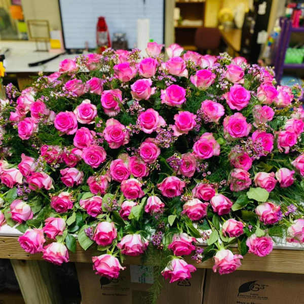 Large mound of pink roses with small filler flowers on a table