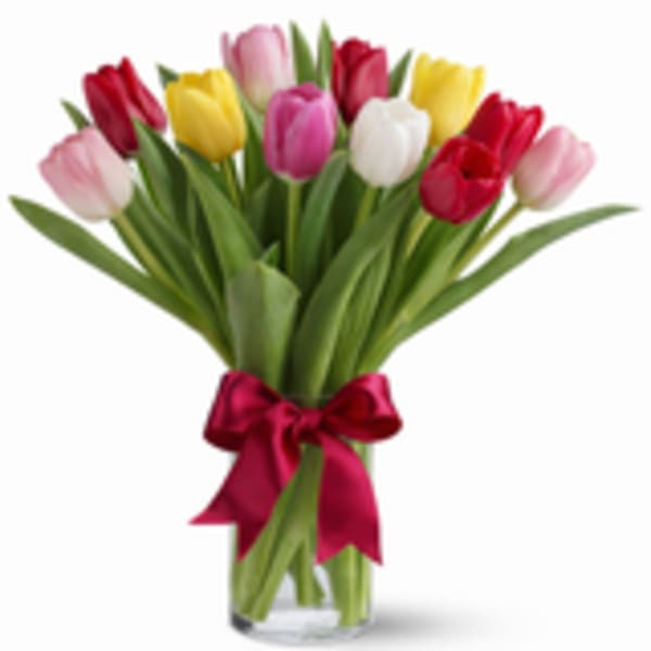 Bouquet of multicolored tulips tied with a red ribbon in a clear vase