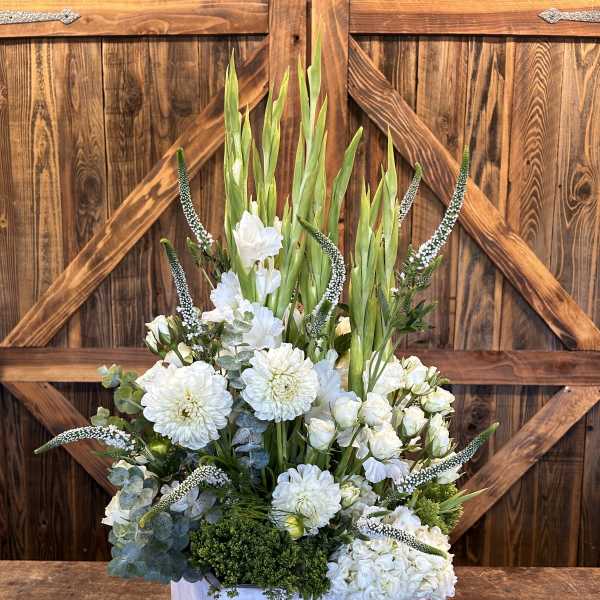 White floral arrangement in a white wooden box with tall green spikes