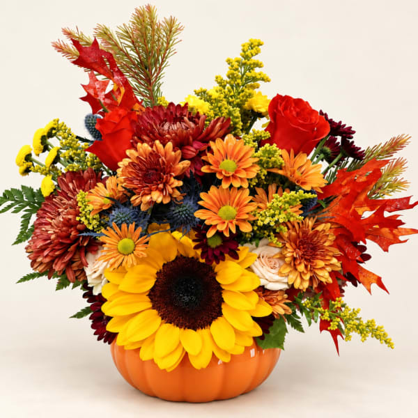 Autumn bouquet with sunflowers, chrysanthemums, and roses in a pumpkin vase