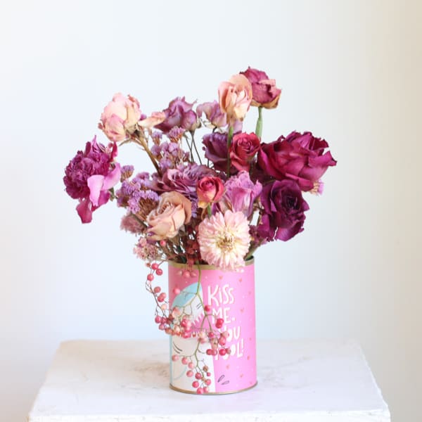 Pink and purple roses in a decorated tin can vase