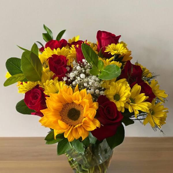 Bouquet of red roses and yellow sunflowers in a clear glass vase