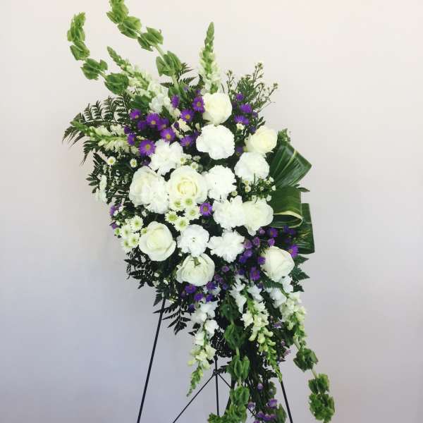 Standing floral spray with white roses and purple daisies on a metal easel