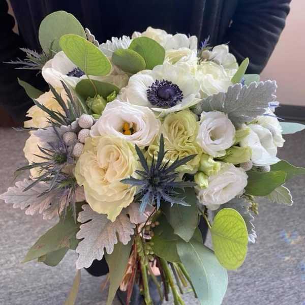 Handheld bouquet of white flowers with green and blue-gray foliage