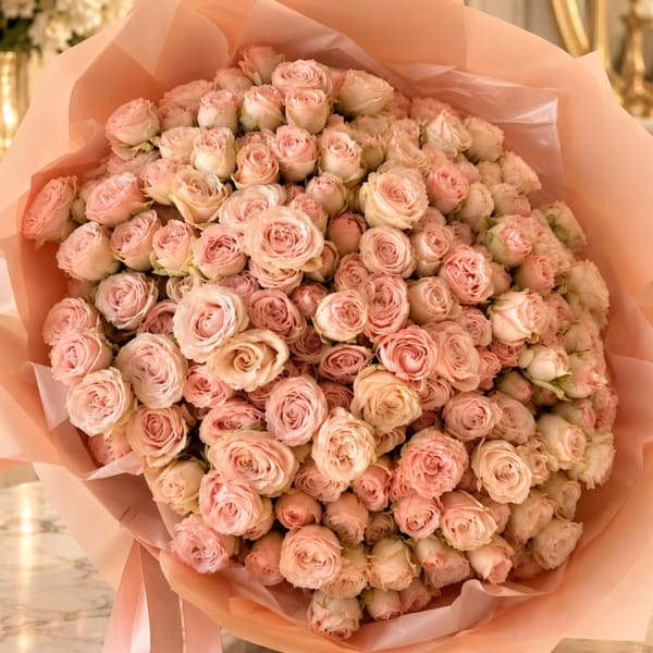 Large bouquet of pale pink roses wrapped in peach paper