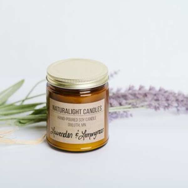 Amber jar soy candle with gold lid beside lavender sprigs on a light surface