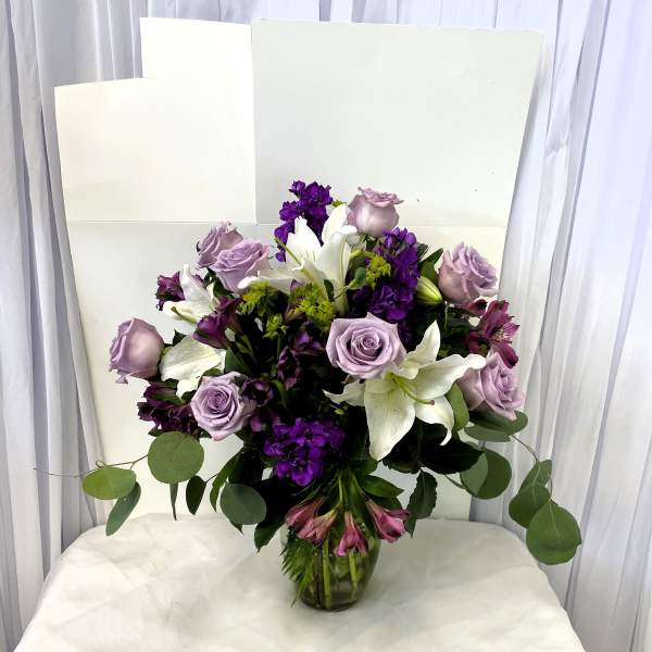 Lavender roses and white lilies in a glass vase