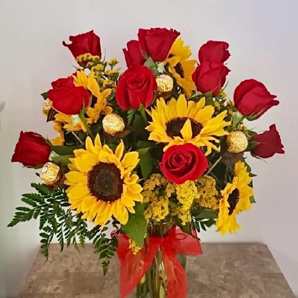 Bouquet of red roses and yellow sunflowers in a glass vase