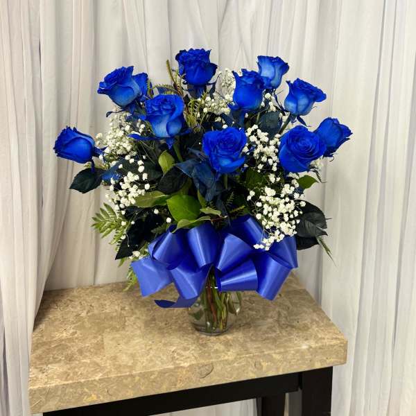 Blue roses in a glass vase with a large blue ribbon