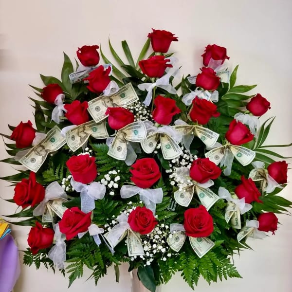 Red roses arranged in a tall vase with dollar bills and white bows