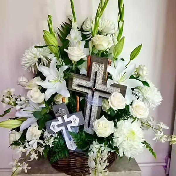 White floral arrangement with crosses in a wicker basket