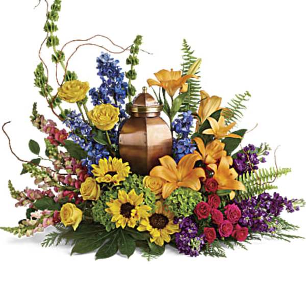 Low ring of colorful lilies, roses, sunflowers, and other blooms surrounding a bronze urn.