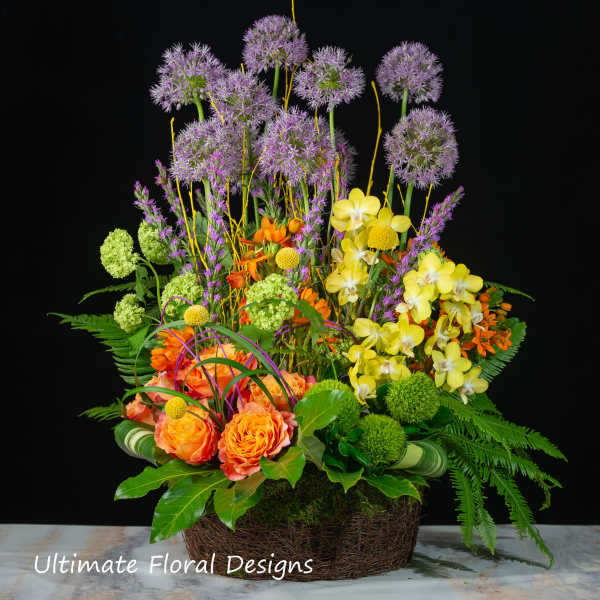 Colorful floral arrangement in a woven basket with tall purple blooms and orange roses