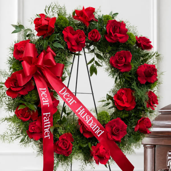 Red rose wreath with a red ribbon on a stand