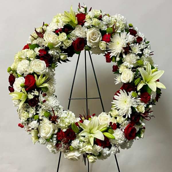 Large floral wreath with white and red flowers on a black stand