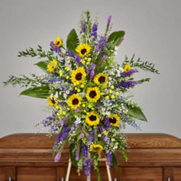 Standing spray with sunflowers and purple flowers on an easel