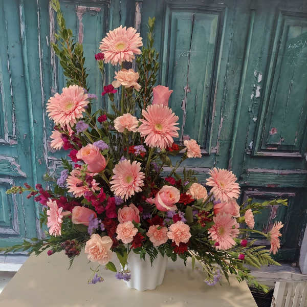 Large pink floral arrangement in a white vase
