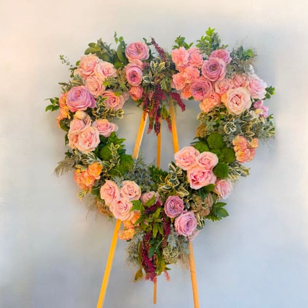 Heart-shaped floral wreath on an easel with pink and lavender roses
