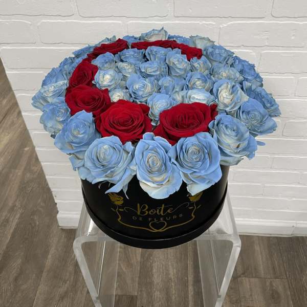 Round box of blue and red roses on a clear stand