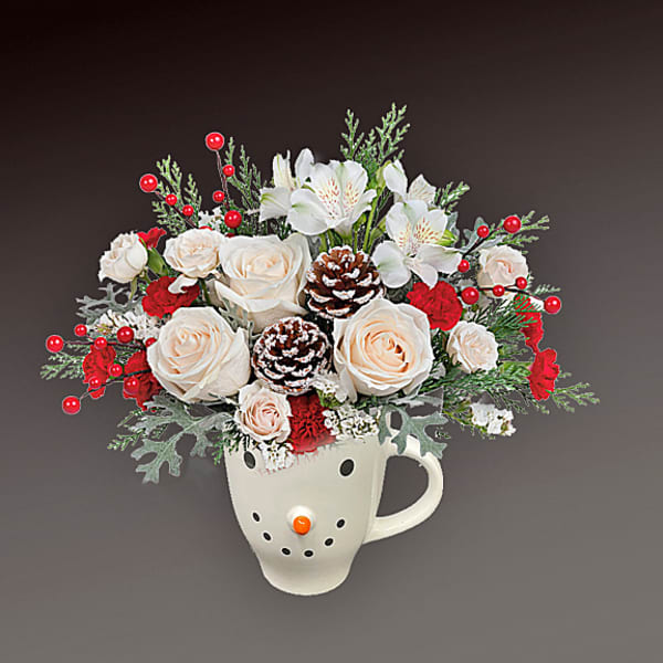 White roses and red flowers arranged in a snowman mug