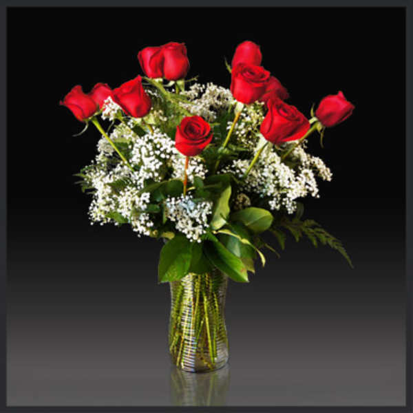 Red roses arranged in a glass vase with white filler flowers