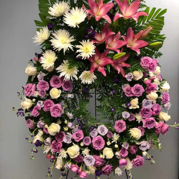 Large standing floral wreath with pink lilies, white spider mums, and roses