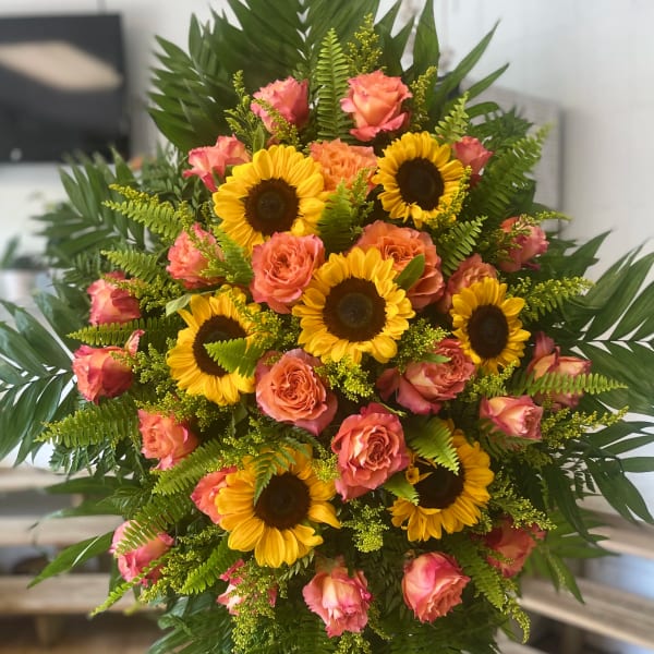 Standing bouquet of sunflowers and pink roses with lush greenery