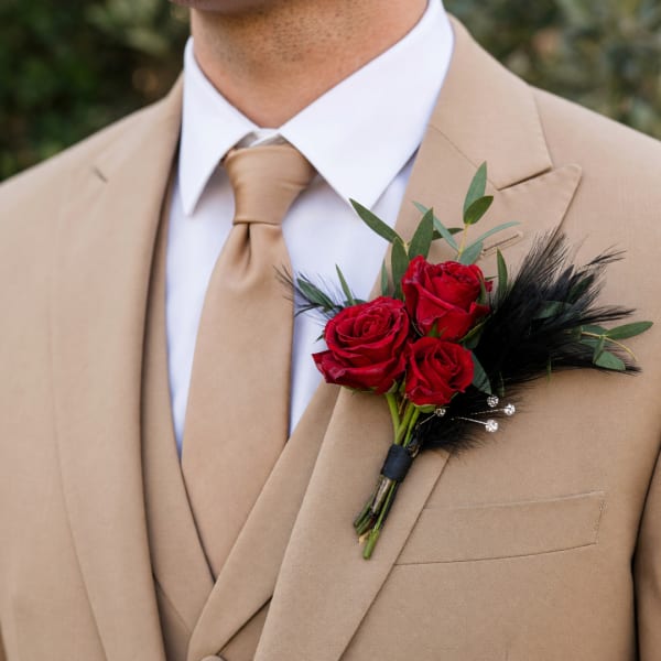 Red rose boutonniere pinned to a tan suit jacket