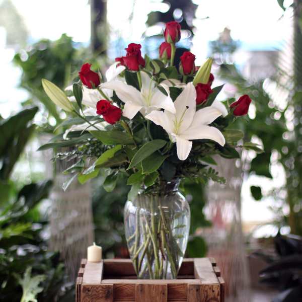 Red roses and white lilies arranged in a clear glass vase