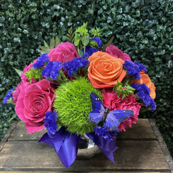 Bright mixed rose arrangement with purple accents in a vase