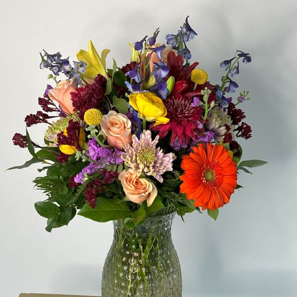 Mixed bouquet in a textured glass vase with orange gerbera daisies and roses