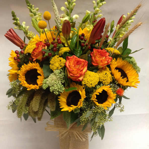 Sunflower and rose arrangement in a burlap-wrapped vase