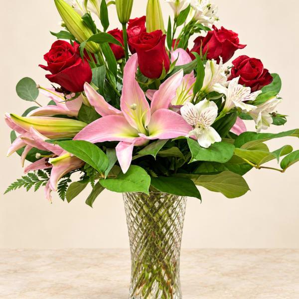 Red roses and pink lilies in a clear glass vase