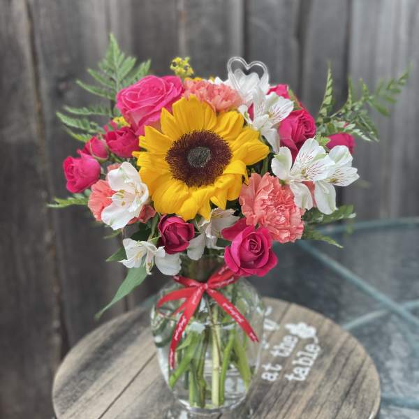 Sunflower and pink rose bouquet in a glass vase