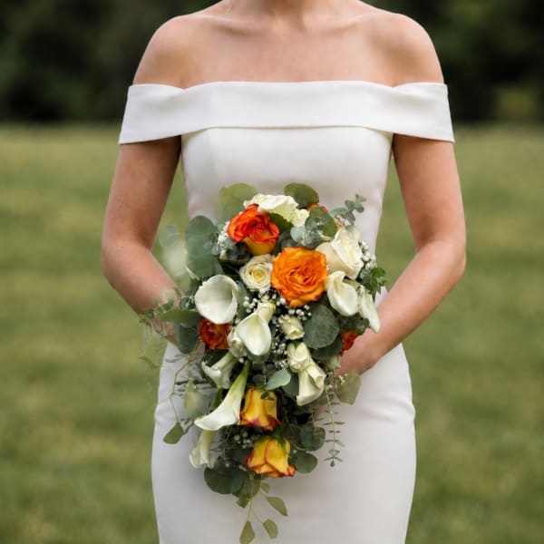 Bride holding a cascading bouquet of orange and white flowers