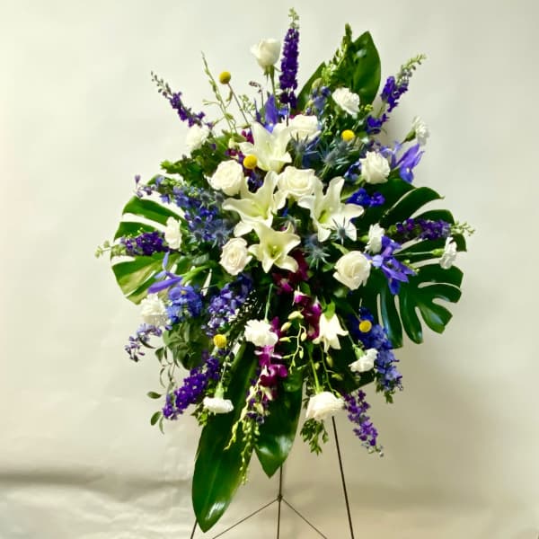 Standing floral spray with white lilies, roses, and purple flowers