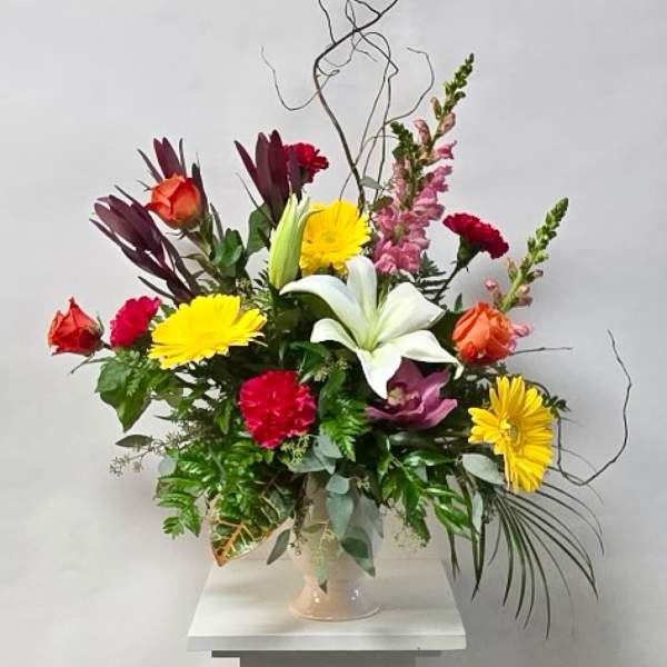 Mixed bouquet with lilies, roses, and daisies in a glass vase