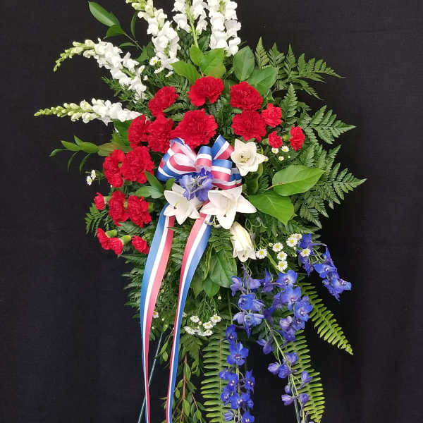 Standing floral spray with red, white, and blue flowers on a black background